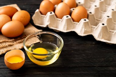Ahşap masa üzerinde yumurta ile bir kırık kahverengi ve yumurta sarısı