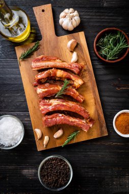 Tahtadaki malzemelerle birlikte kızartılmaya hazır taze çiğ domuz pirzolası.