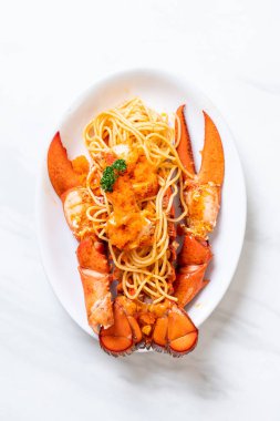 Beyaz tabakta karides yumurtalı ıstakoz spagettisi.