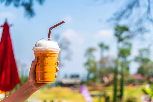 hand holding iced Thai milk tea cup