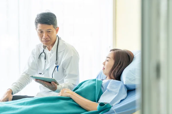 Asiatique médecin principal assis sur le lit d'hôpital et de discuter avec — Photo
