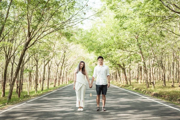 Happy Asian couple in love on road with tree arch