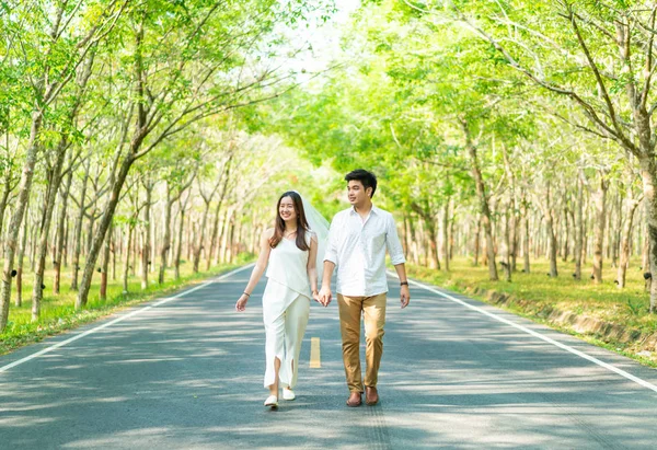 Happy Asian couple in love on road with tree arch