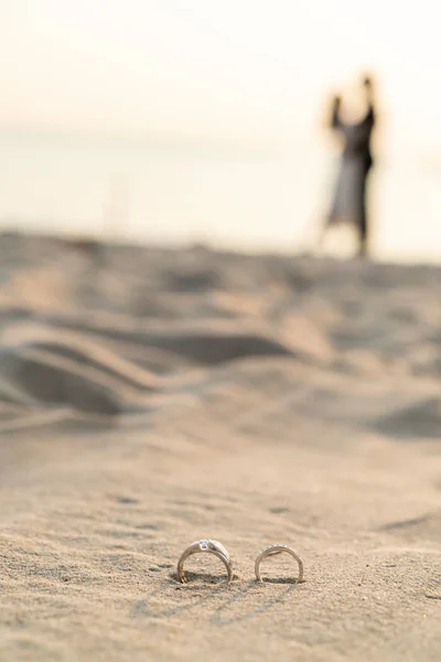 Anéis na praia com noiva e noivo no fundo — Fotografia de Stock
