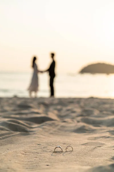 Δαχτυλίδια στην παραλία με τη νύφη και το γαμπρό στο παρασκήνιο — Φωτογραφία Αρχείου