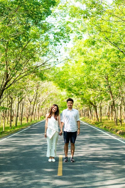 Счастливая азиатская пара влюбленная на дороге с дугой дерева — стоковое фото