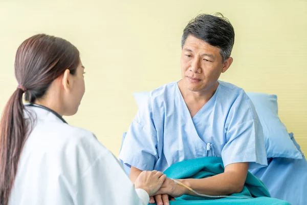 Vrouwelijke arts geruststellend op haar senior patiënt hand — Stockfoto