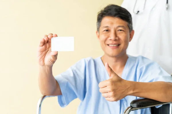 Asiático paciente sênior cadeira de rodas sorrindo com cartão de crédito — Fotografia de Stock