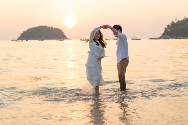 Mutlu çift balayı gidiş tropikal kum plajı üzerinde su içinde seyahat.