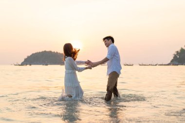 Mutlu çift balayı gidiş tropikal kum plajı üzerinde su içinde seyahat.