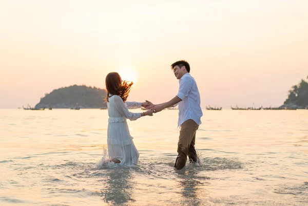 Mutlu çift balayı gidiş tropikal kum plajı üzerinde su içinde seyahat.