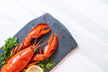 bitkisel ve siyah arduvaz plaka üzerinde limon ile ıstakoz