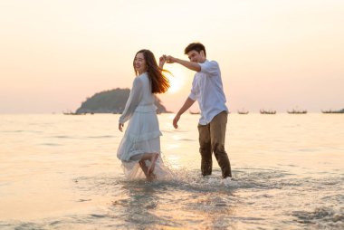 Mutlu çift balayı gidiş tropikal kum plajı üzerinde su içinde seyahat.