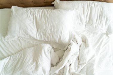 Yatakta beyaz yastık ve battaniye ile dağınık yatak 