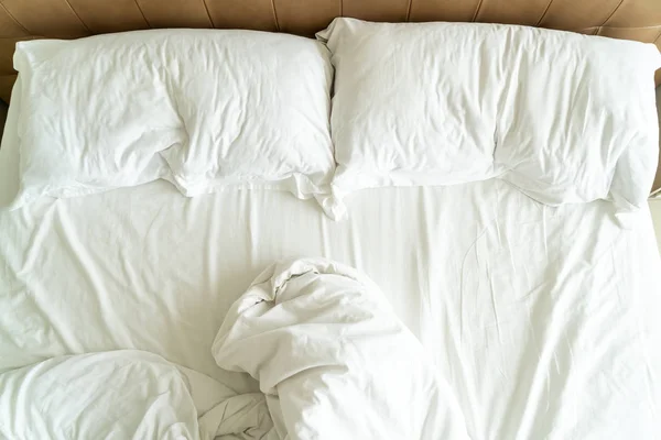 Грязная кровать с белой подушкой и одеялом на кровати — стоковое фото