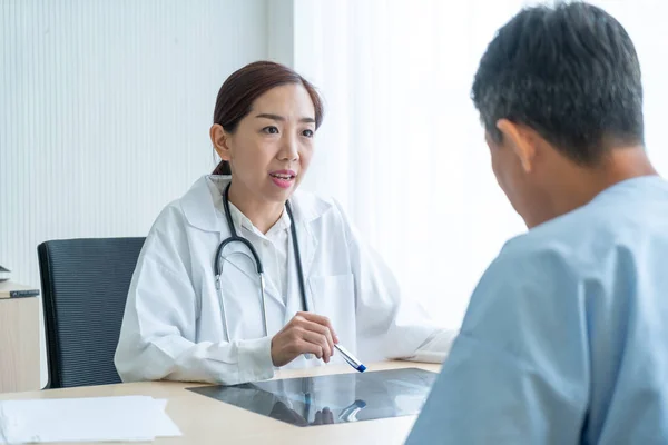 Asian female doctor and patient discussing something while sitti Stock Image