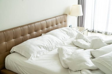 Yatakta beyaz yastık ve battaniye ile dağınık yatak 