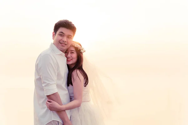 outdoor portrait of asian bride and groom looking at camera