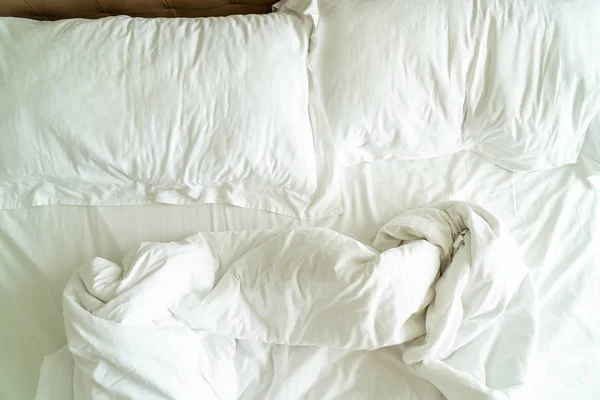 Грязная кровать с белой подушкой и одеялом на кровати — стоковое фото