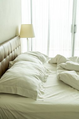 Yatakta beyaz yastık ve battaniye ile dağınık yatak 