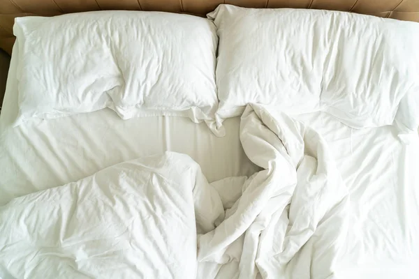 Cama desordenada con almohada blanca y manta en la cama — Foto de Stock