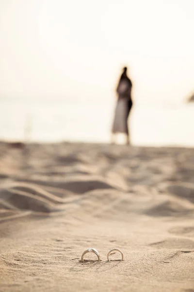 Кольца на пляже с невестой и женихом на заднем плане — стоковое фото