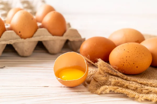 Brown eggs with one broken and egg yolk — Stock Photo, Image