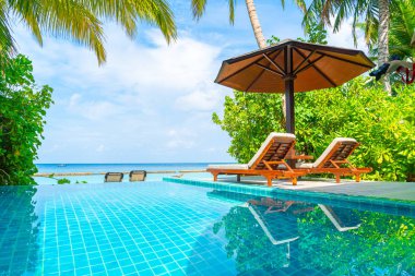Maldivler yüzme havuzu ve deniz arka plan ile plaj sandalyesi