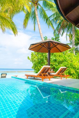 Maldivler yüzme havuzu ve deniz arka plan ile plaj sandalyesi