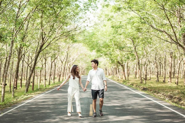 Happy Asian couple in love on road with tree arch