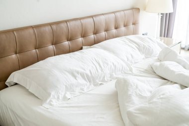 Yatakta beyaz yastık ve battaniye ile dağınık yatak 