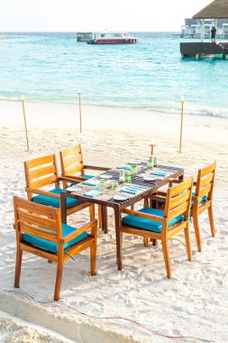 Maldiv 'de deniz manzaralı arka plan ile sahilde ahşap masa ve sandalye