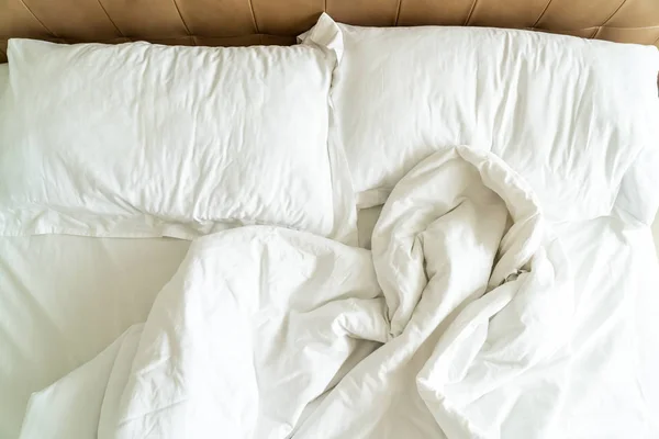 Cama desordenada con almohada blanca y manta en la cama — Foto de Stock