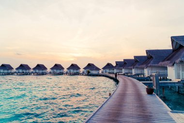Su bungal ile Maldivler Adası üzerinde güzel tropikal günbatımı