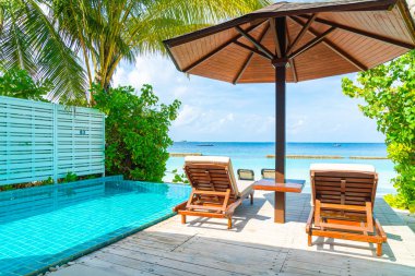 Maldivler yüzme havuzu ve deniz arka plan ile plaj sandalyesi