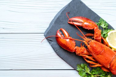 bitkisel ve siyah arduvaz plaka üzerinde limon ile ıstakoz