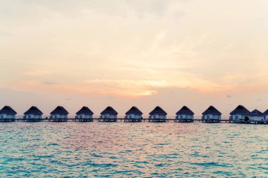 Su bungal ile Maldivler Adası üzerinde güzel tropikal günbatımı