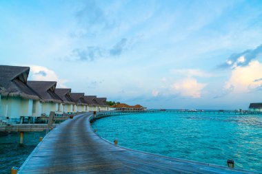 Su bungal ile Maldivler Adası üzerinde güzel tropikal günbatımı
