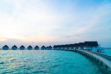 Su bungal ile Maldivler Adası üzerinde güzel tropikal günbatımı