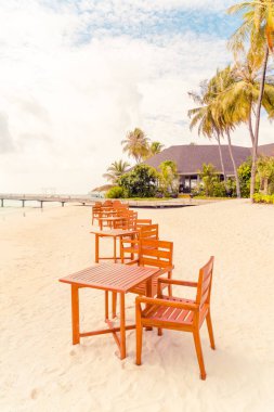 Maldiv 'de deniz manzaralı arka plan ile sahilde ahşap masa ve sandalye