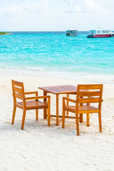 Maldiv 'de deniz manzaralı arka plan ile sahilde ahşap masa ve sandalye