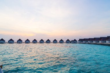Su bungal ile Maldivler Adası üzerinde güzel tropikal günbatımı