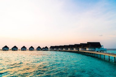 Su bungal ile Maldivler Adası üzerinde güzel tropikal günbatımı