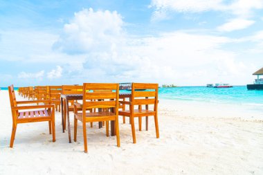 Maldiv 'de deniz manzaralı arka plan ile sahilde ahşap masa ve sandalye