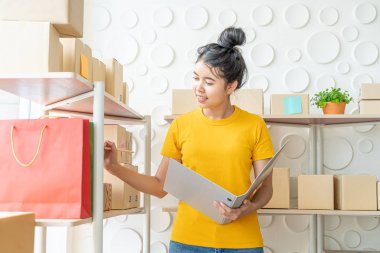  Genç Asyalı kadın ambar stok raf üzerinde mal kontrol