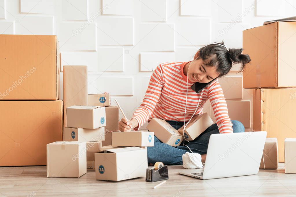 Asian Women business owner working at home with packing box on w