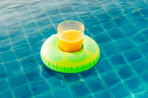 Orange juice glass with swim ring at outdoor swimming pool — Stock Photo, Image