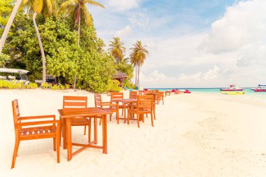 Maldiv 'de deniz manzaralı arka plan ile sahilde ahşap masa ve sandalye