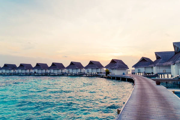 Su bungal ile Maldivler Adası üzerinde güzel tropikal günbatımı
