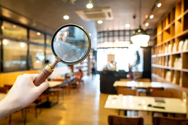 Magnifying glass with cafe restaurant with abstract blur cafe re